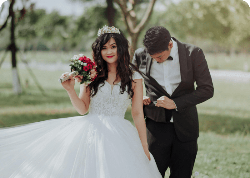 Frame-1618873631 A man and woman in wedding attire holding flowers.